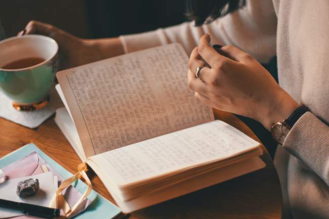 Journal filled with written text lying on a table with coffee and breakfast
